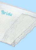 A close up image of Berry Sorbet’s Sugar Bride briefs over a blue background that accentuates the blue bride embroidery on the white ribbed cotton briefs.