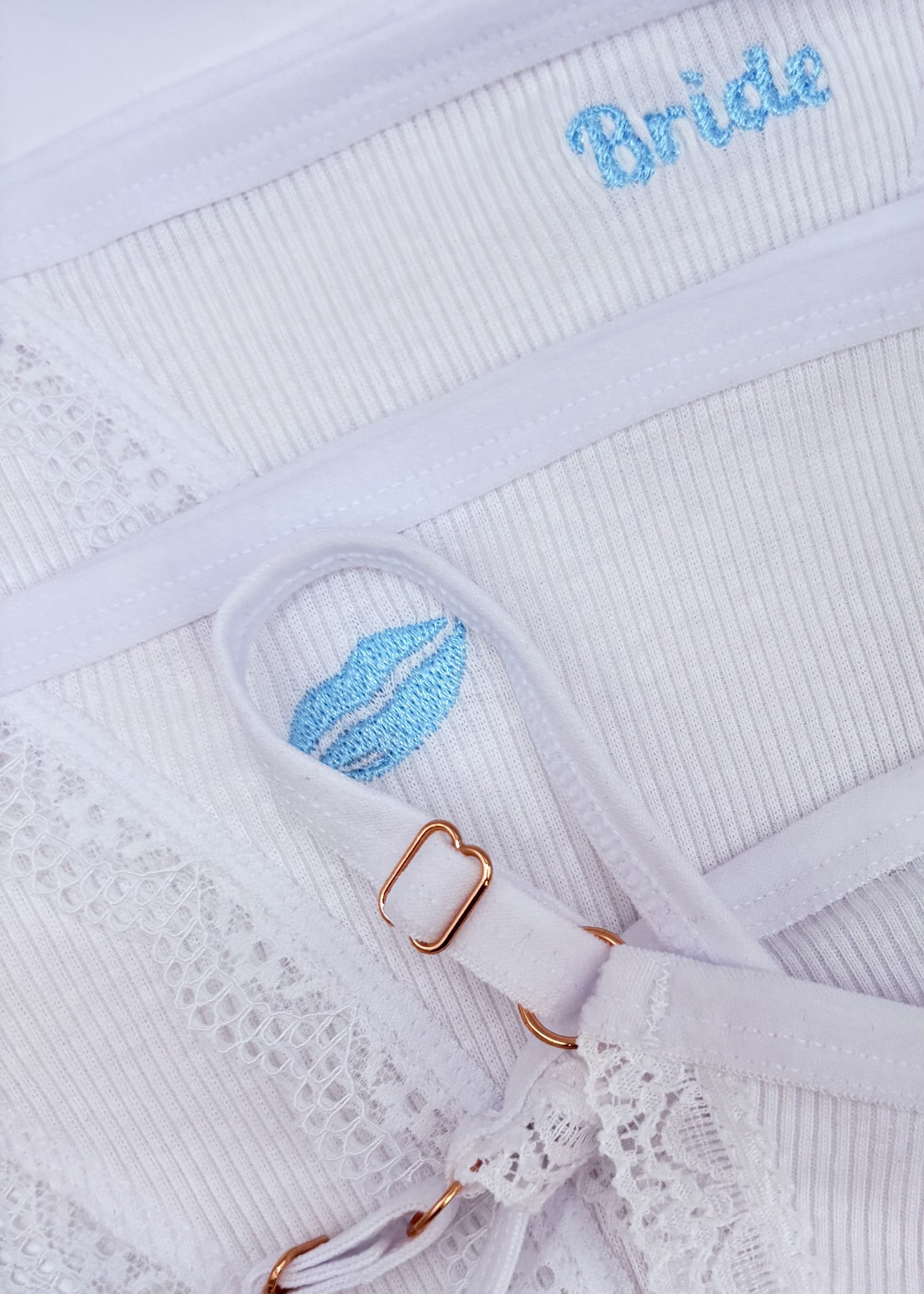 A close up image of Berry Sorbet’s Sugar Lips embroidered cotton thong in white and light blue.